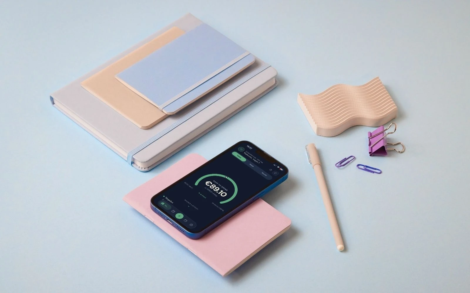 A phone among notebooks and a pen on a desk, its screen showing the Prsperous safe-to-spend gauge.