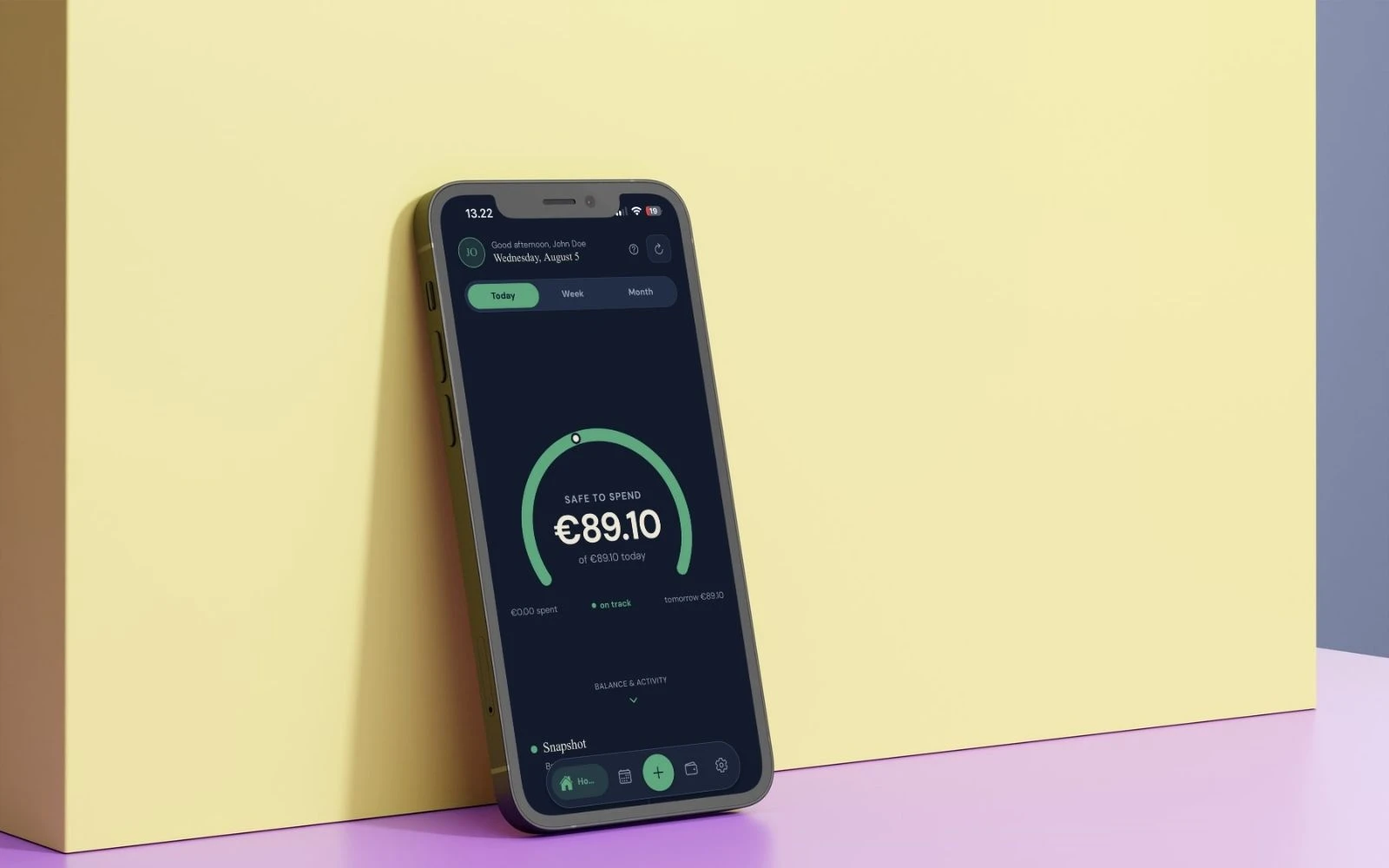 A phone leaning against a yellow wall, its screen showing the Prsperous safe-to-spend gauge at €89.10 for today.